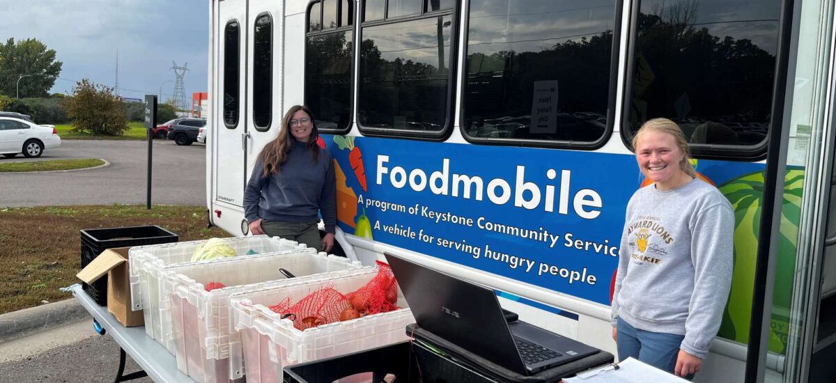 Two people standing outside of the mobile food shelf bus