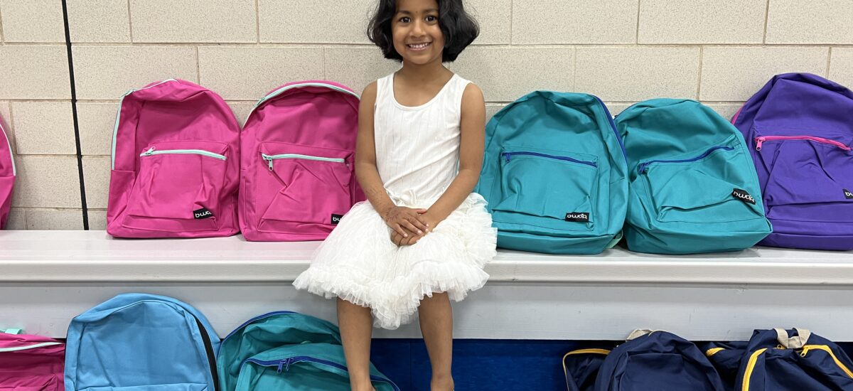 Photo of young girl sitting by backpacks